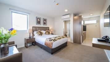 A modern hotel room with a large bed, bedside tables, a desk, and a TV.