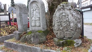 Un cementerio con monumentos de piedra, incluyendo una gran esfera de piedra con grabados y una lápida rectangular con inscripciones.