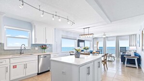 A modern kitchen with a central island, white cabinetry, and a view to the sea. - Paradise Beach Club - Oceanfront and Penthouse Deluxe Condos with Heated Pool (Satellite Beach)