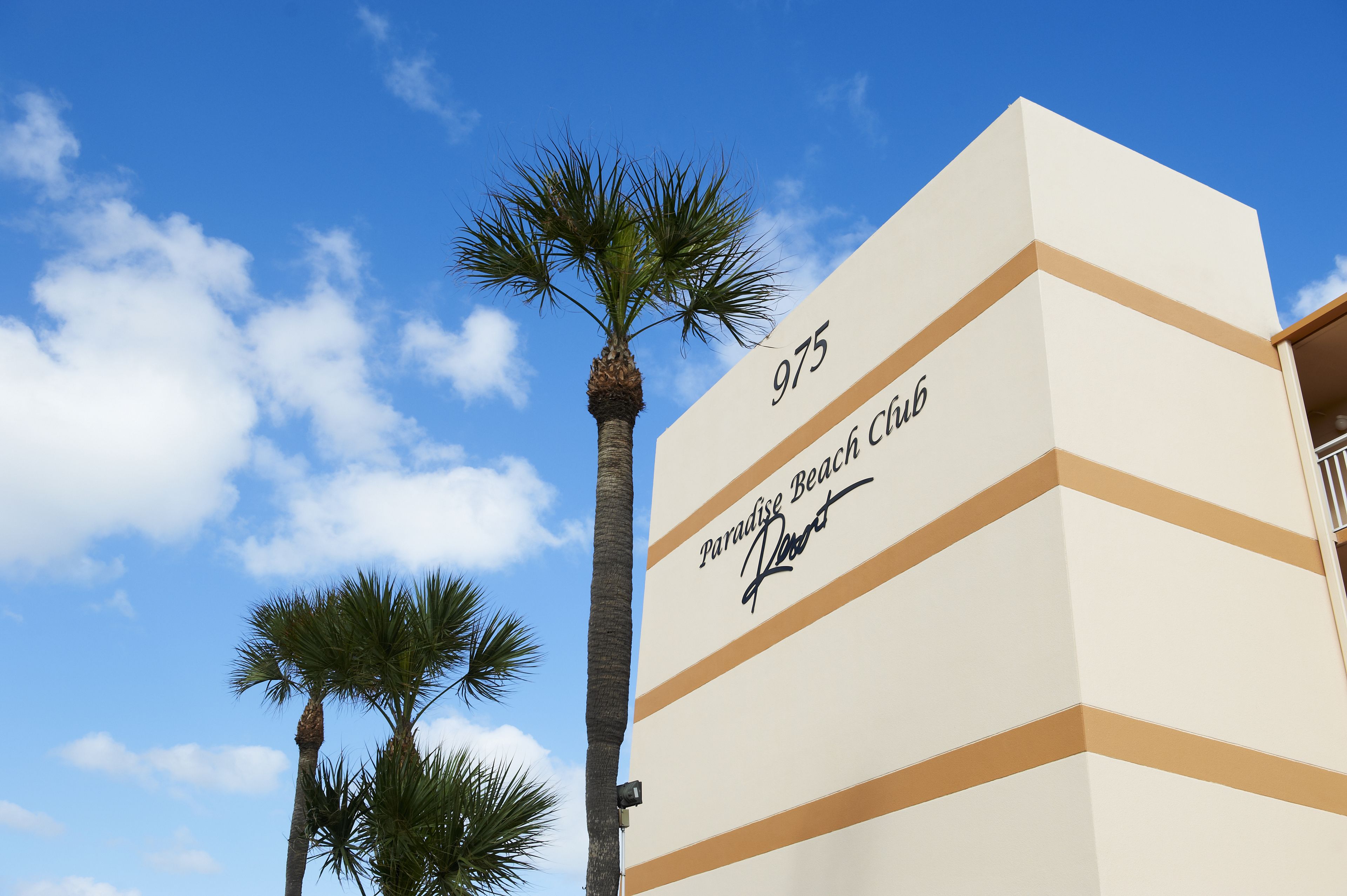 A building with the number 975 and the name 'Paradise Beach Resort' on its facade.