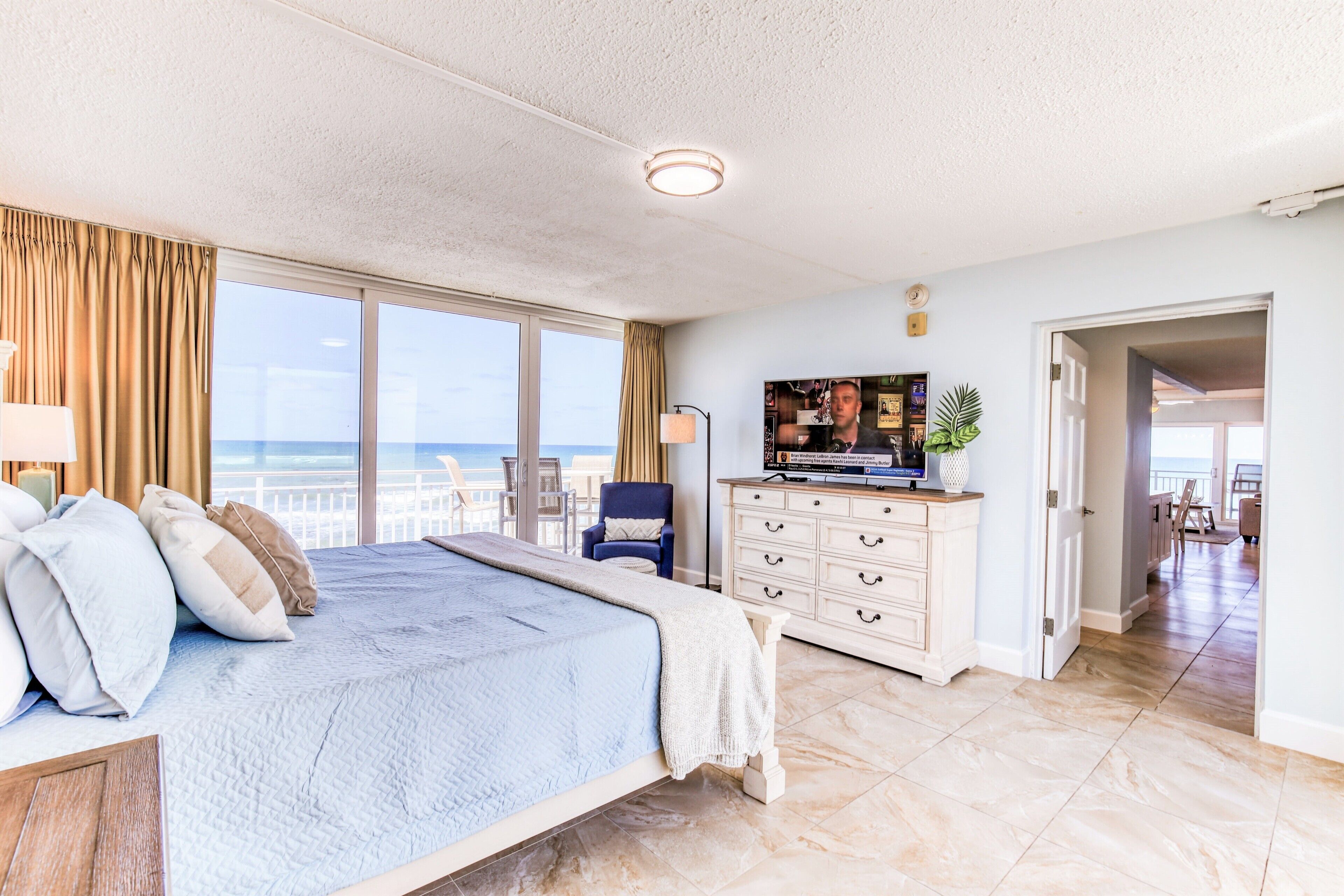 A spacious bedroom with a large bed, a TV, and a view of the ocean.