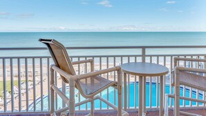 A balcony with a view of the ocean, a pool, and beach chairs. - Paradise Beach Club - Oceanfront and Penthouse Deluxe Condos with Heated Pool (Satellite Beach)