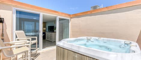 Un jacuzzi, mobiliario exterior y una puerta corrediza que da a un espacio interior.
