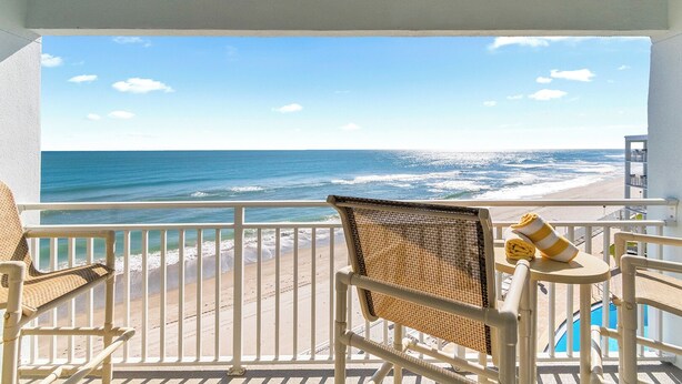 A balcony with a view of the beach and ocean, white railings, and wicker chairs. - Paradise Beach Club - Oceanfront and Penthouse Deluxe Condos with Heated Pool (Satellite Beach)