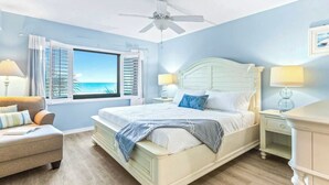 A bedroom with a bed, nightstands, a chair, a window with shutters, and a ceiling fan. - Sandcastles - Cocoa Beach Oceanfront Condos with Heated Pool Tennis Pet-Friendly (Cocoa Beach)