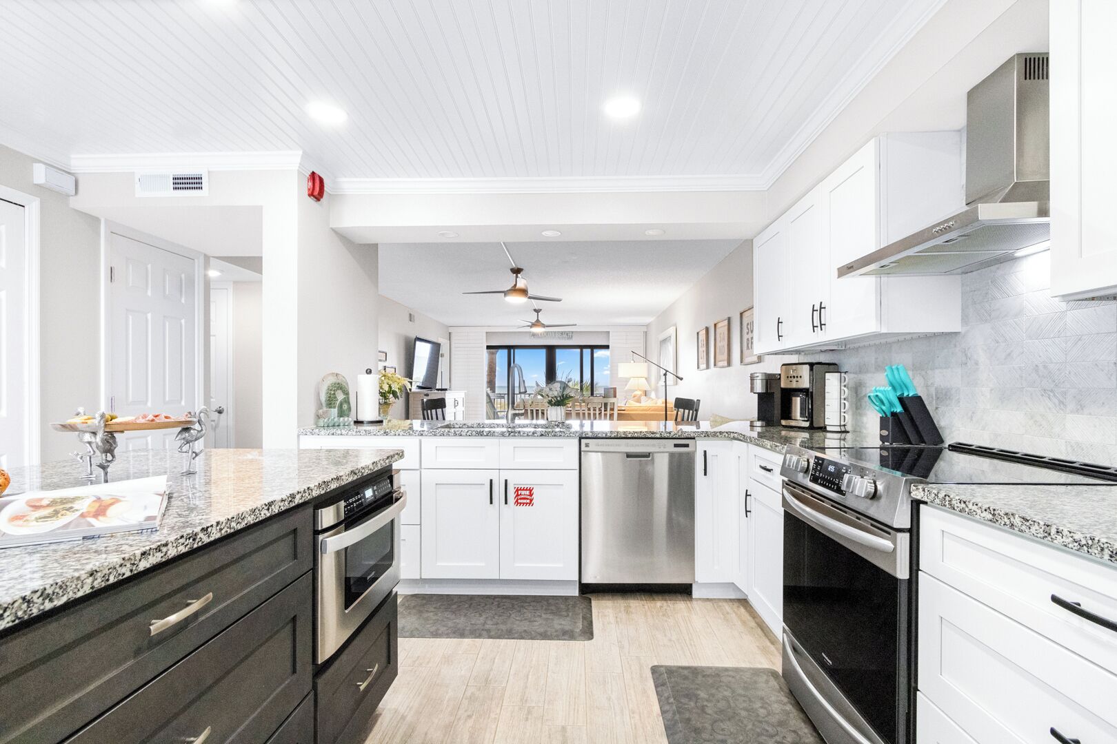 A modern kitchen with granite countertops, stainless steel appliances, and a view to the outside.