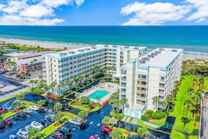 A hotel with a pool, parking lot, and ocean view. - Sandcastles - Cocoa Beach Oceanfront Condos with Heated Pool Tennis Pet-Friendly (Cocoa Beach)