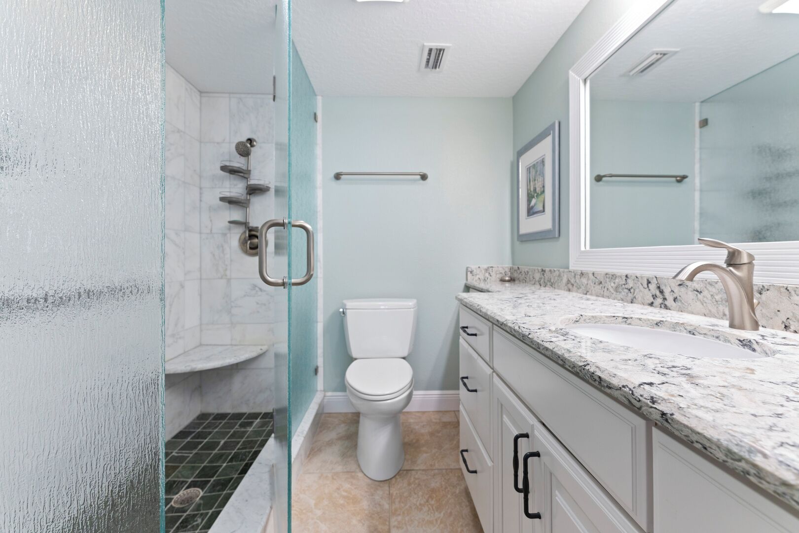 A modern bathroom with a glass shower enclosure, a toilet, and a marble countertop with a sink and faucet.