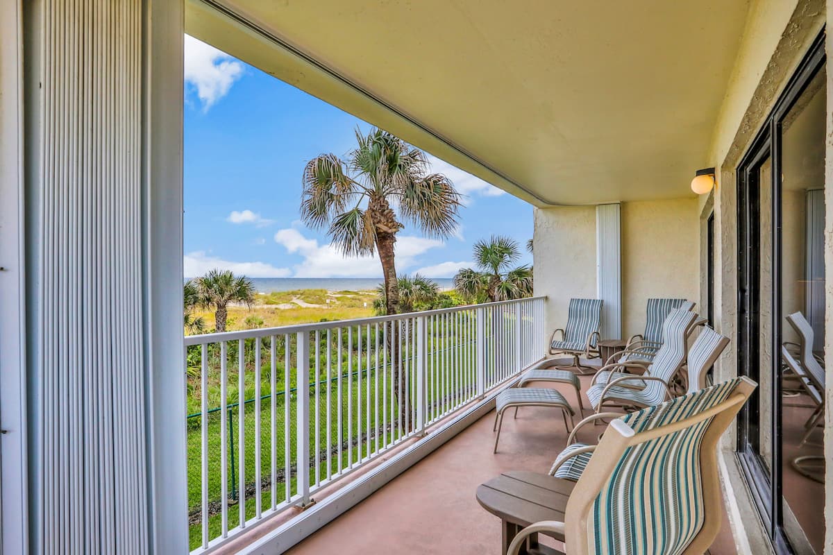 A balcony with chairs and a view of the ocean.