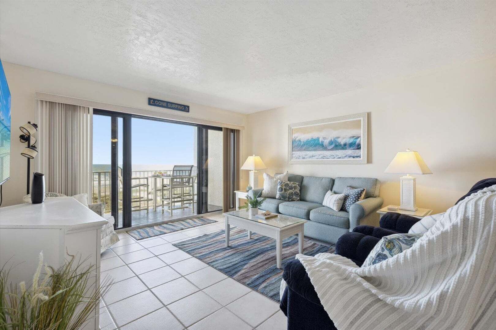 A living room with a sofa, coffee table, and a view of the ocean through a sliding door.