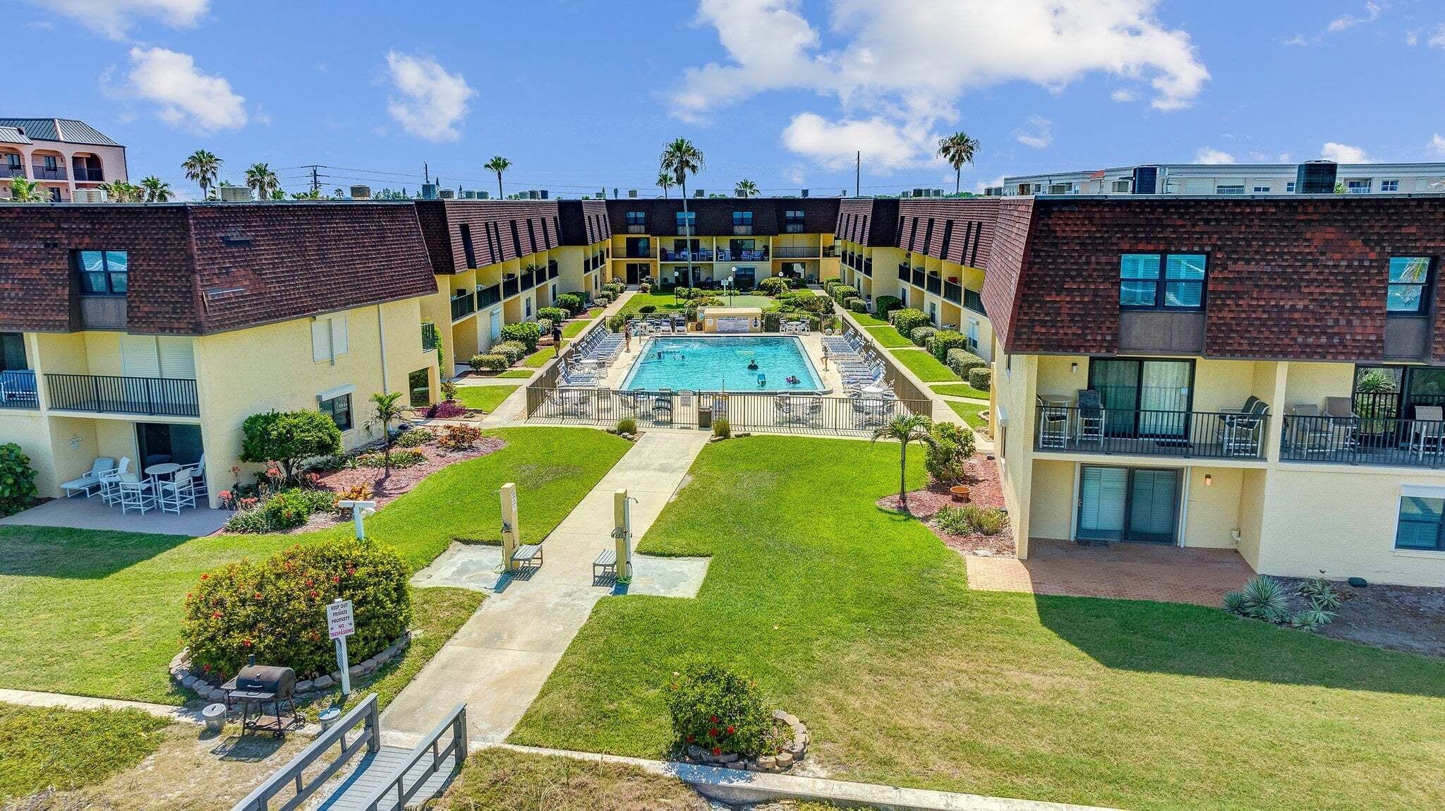 A multi-story building with a central courtyard featuring a swimming pool, outdoor seating, and a barbecue area.