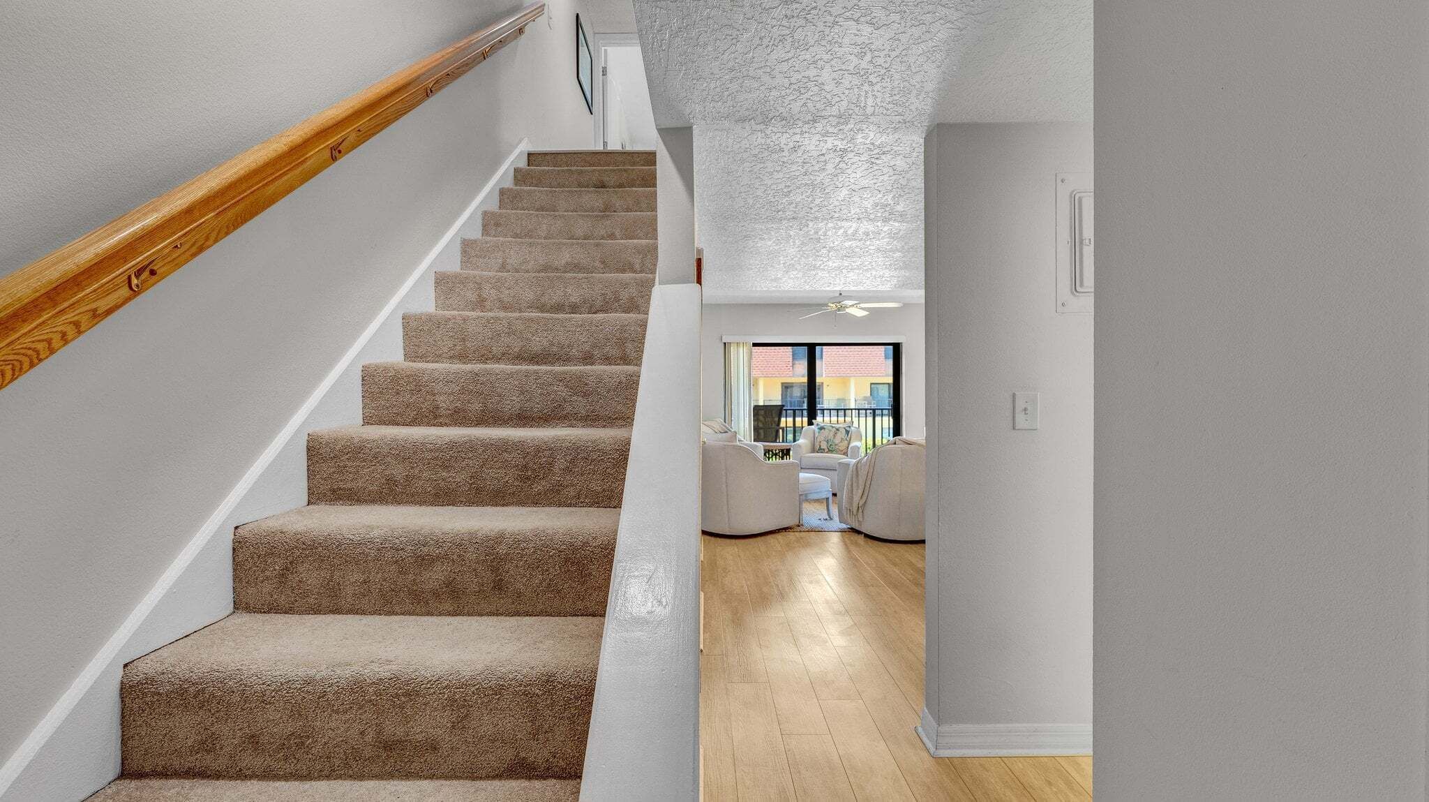 A staircase with carpeted steps and a wooden handrail leading to a room with a view.