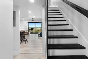 A staircase with black steps leading to a balcony with a view of the ocean.