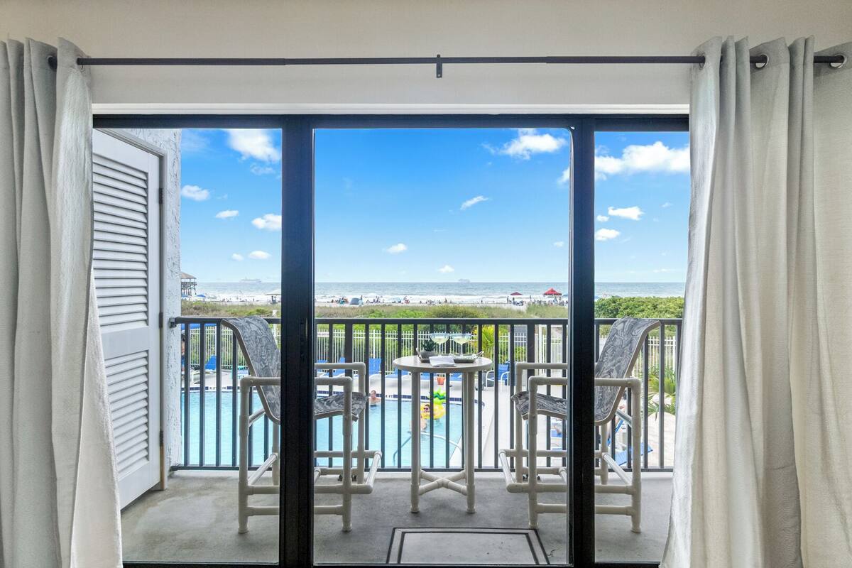 Un balcone con vista sull'oceano, una piscina e due sedie.