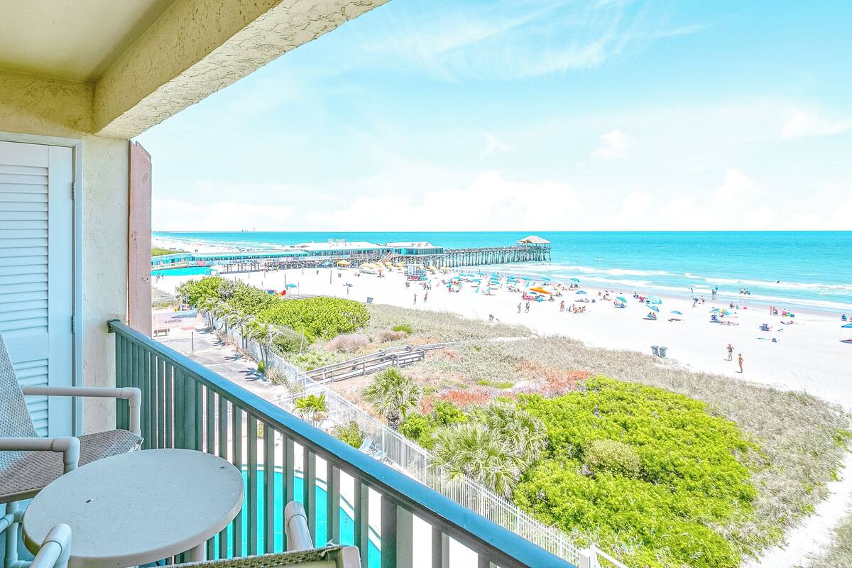 Un balcone con vista su una spiaggia, un molo e una piscina.