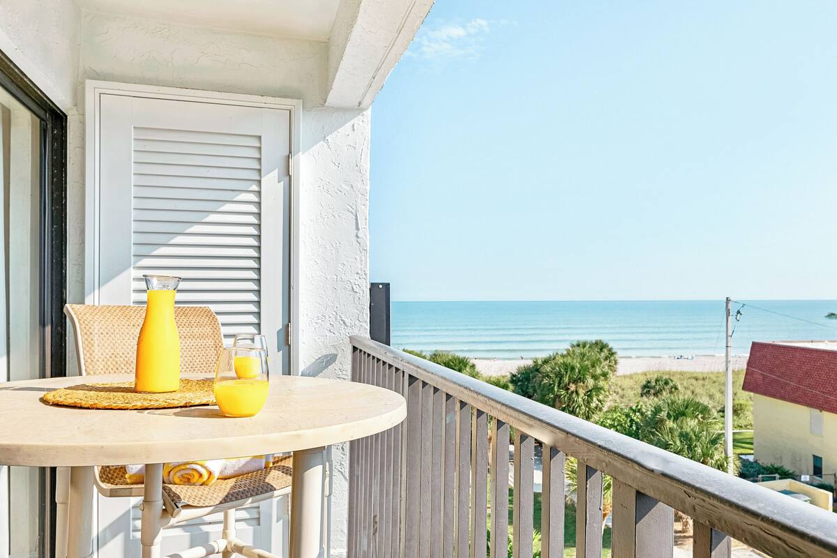 Un balcone con un tavolo apparecchiato per due, con vista sulla spiaggia.