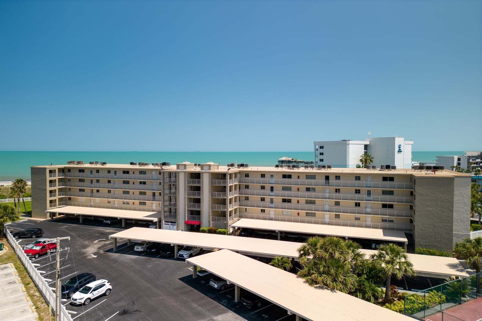 Un hôtel à plusieurs étages, doté d’un parking et offrant une vue sur l’océan.