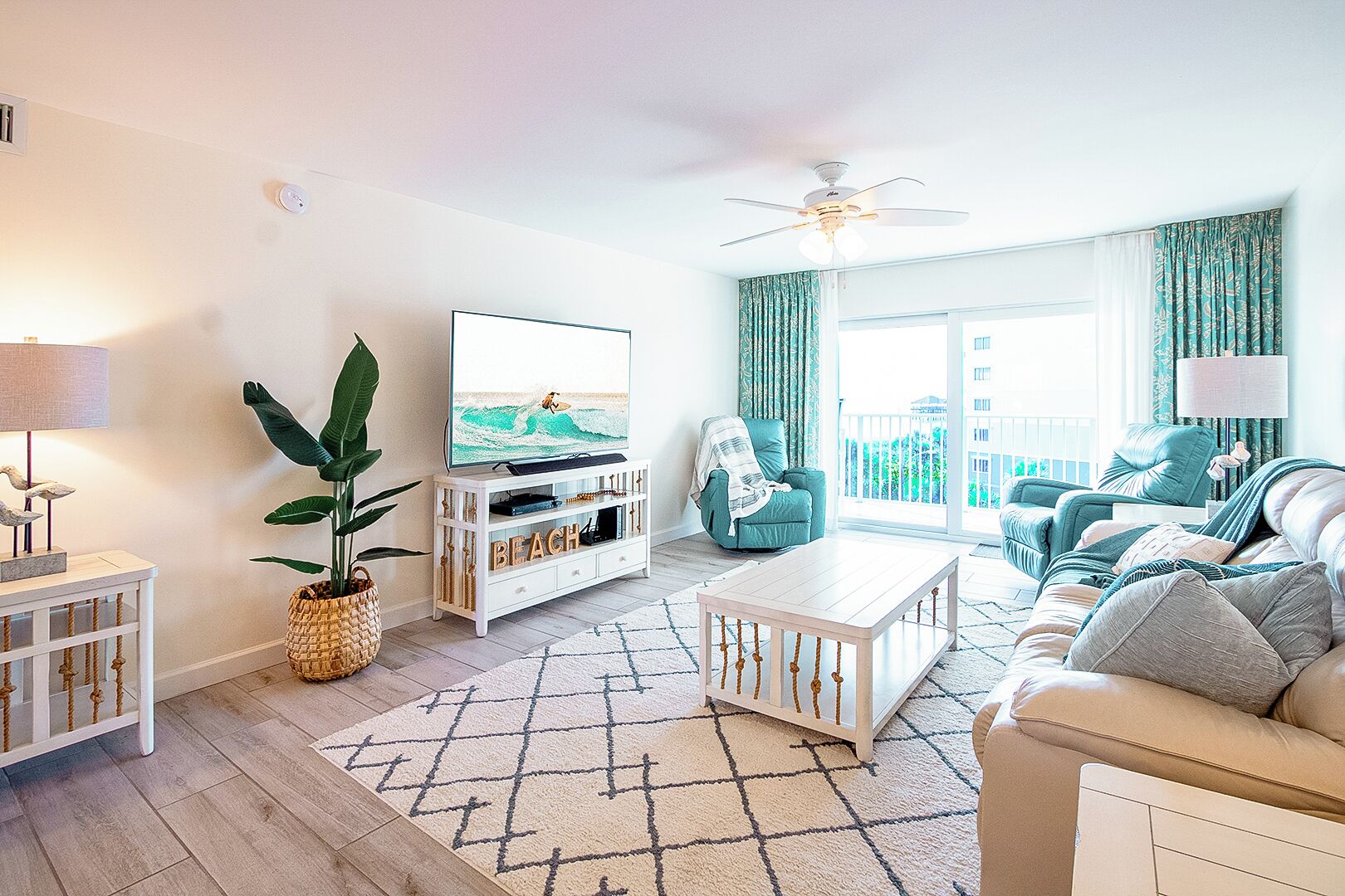 A living room with a TV, a ceiling fan, a sofa, and a coffee table.