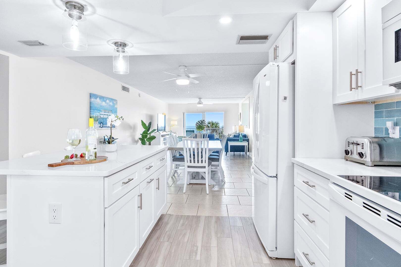 A modern kitchen with white cabinetry, a dining area with a table and chairs, and a view to the outside.