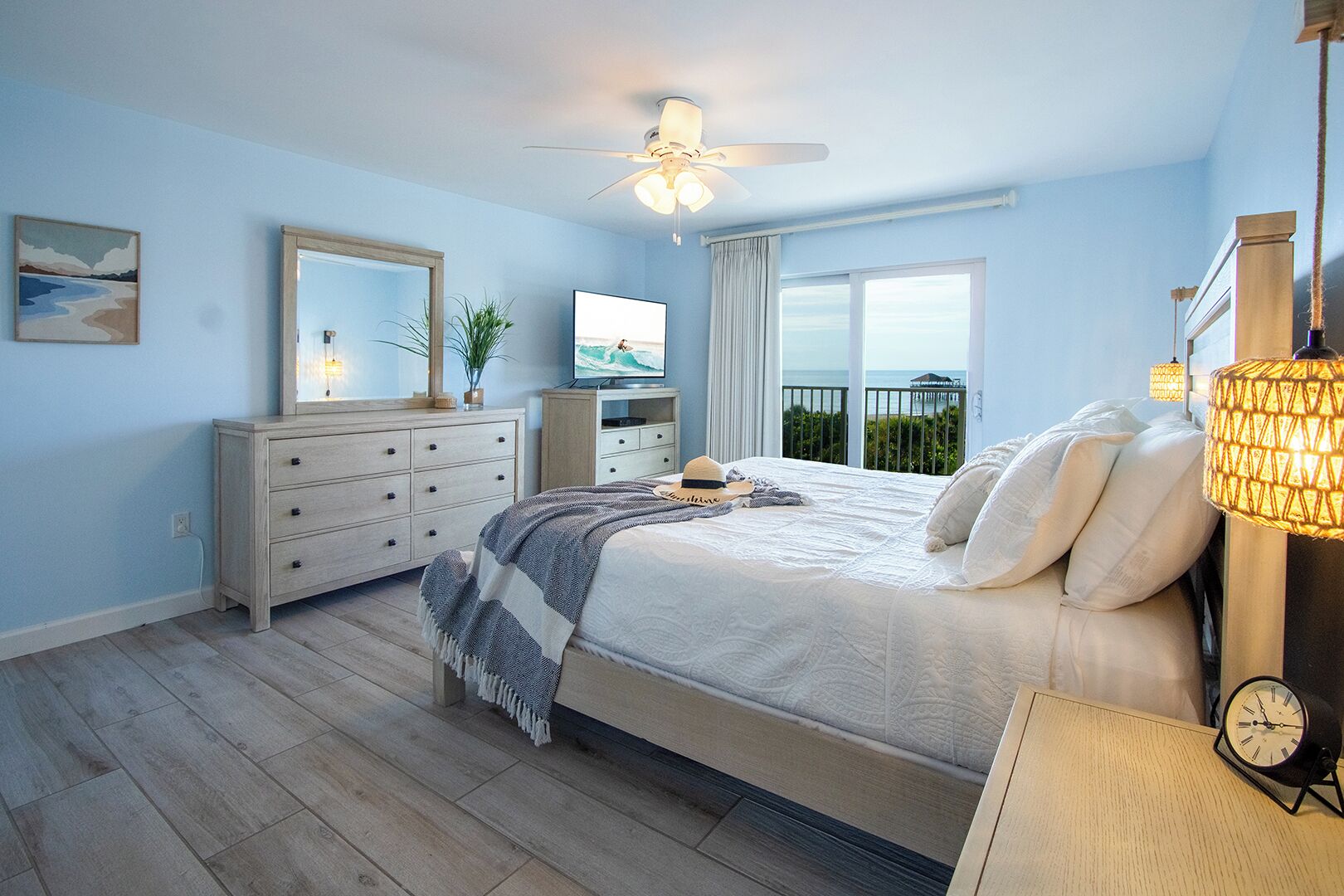 Une chambre avec un lit, une commode, une télévision et un balcon offrant une vue.