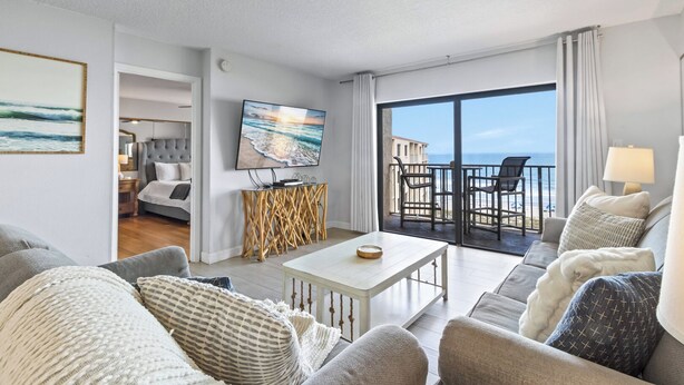 A modern hotel room with a balcony, a television, and a dining area. - Canaveral Towers - Oceanfront Condos with Pool and Mini Golf by Port Canaveral - Cocoa Beach (Cape Canaveral)