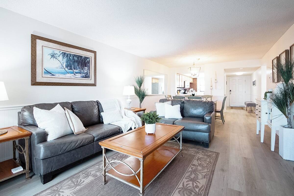 A modern living room with a sofa, coffee table, and a dining area with chairs and a table.