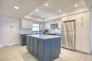 A modern kitchen with a central island, stainless steel appliances, and white cabinetry.