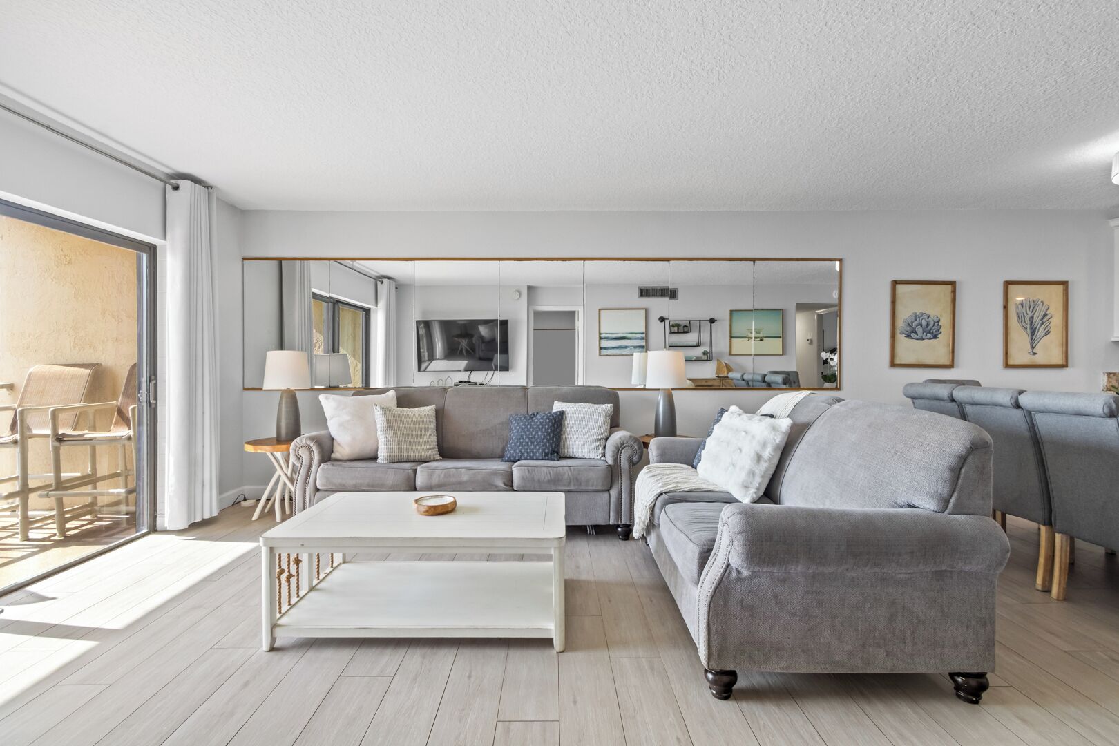 A modern living room with a grey sofa, a white coffee table, and a TV mounted on the wall.