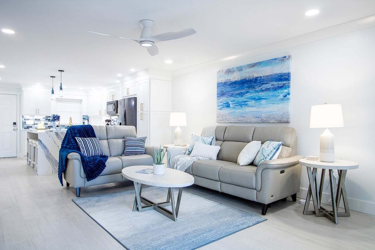A modern living room with a sofa, coffee table, and a painting of the ocean.
