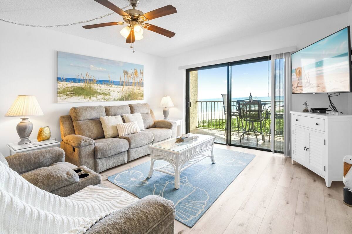A living room with a sofa, coffee table, and a balcony with a view.
