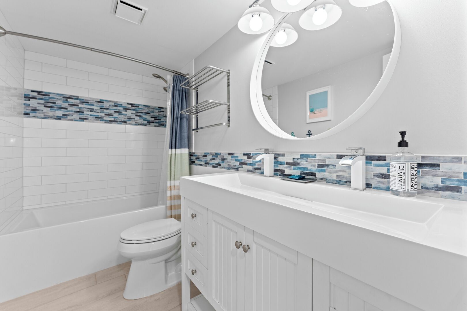 A modern bathroom with a white sink, a large mirror, and a shower area.