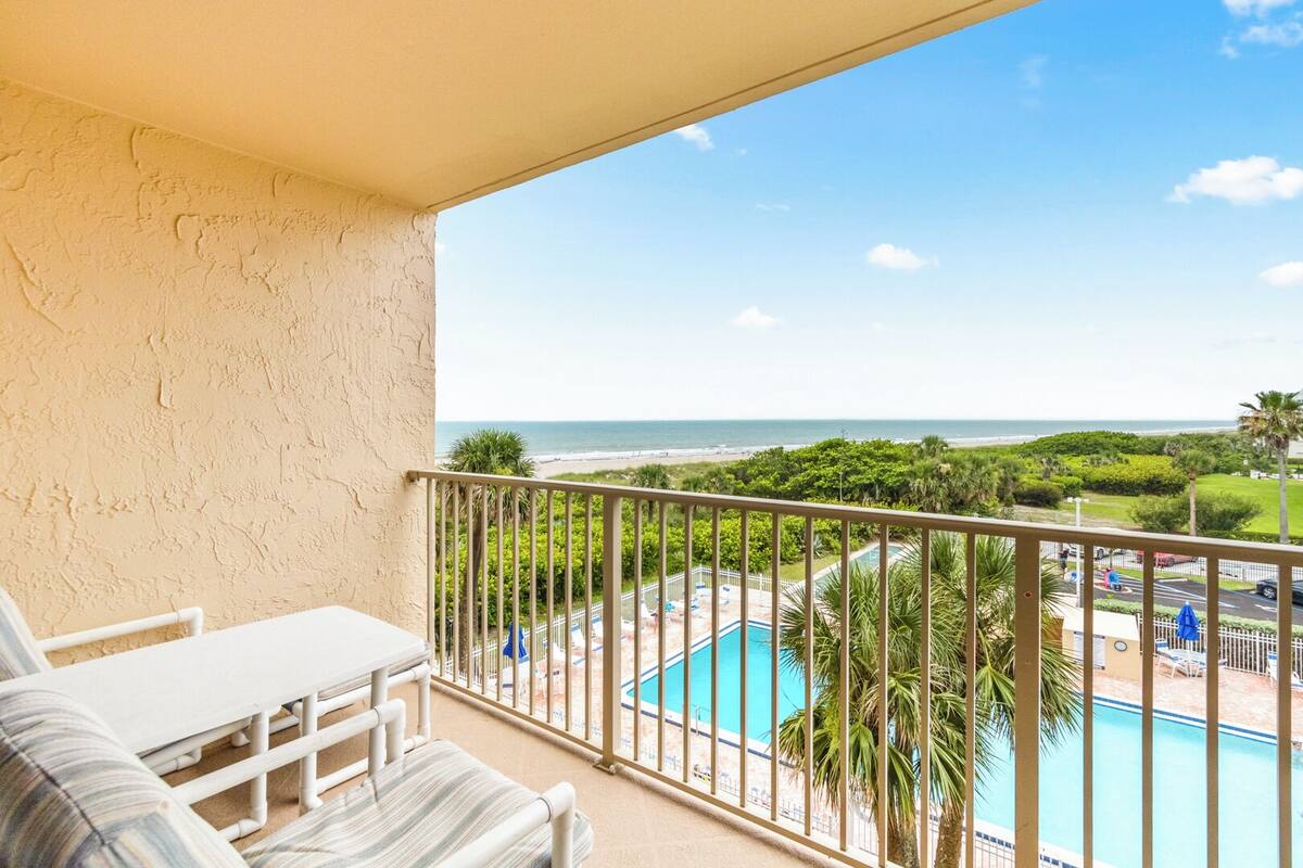 A balcony with a view of a pool and beach.