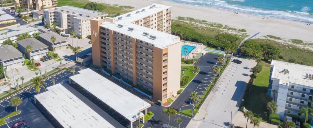 Edificio de Canaveral Towers con vista al mar, estacionamientos y edificios circundantes.