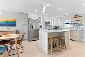 A modern kitchen with a central island, stainless steel appliances, and a dining area with a table and chairs.