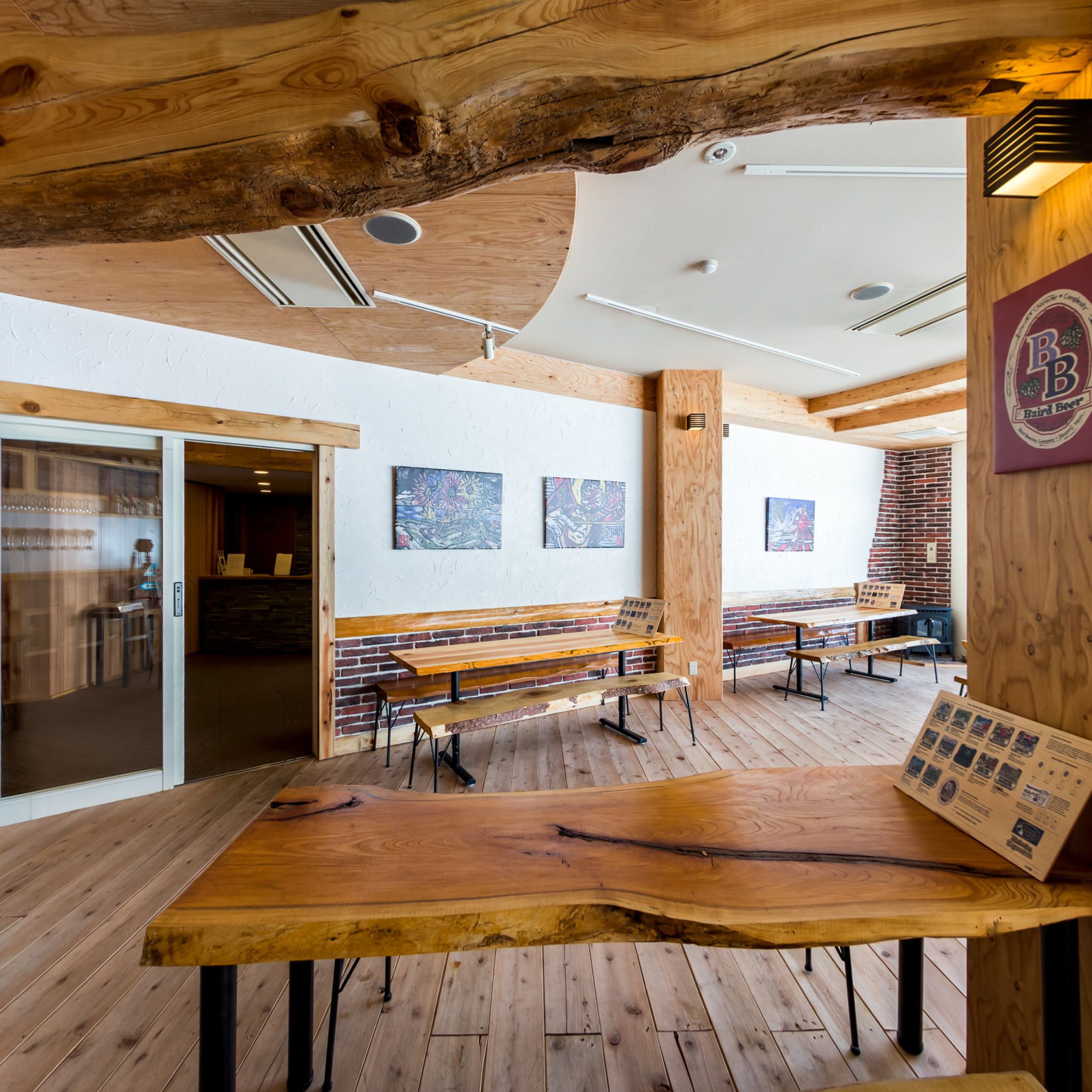 A rustic interior with wooden beams, benches, and a brick wall.