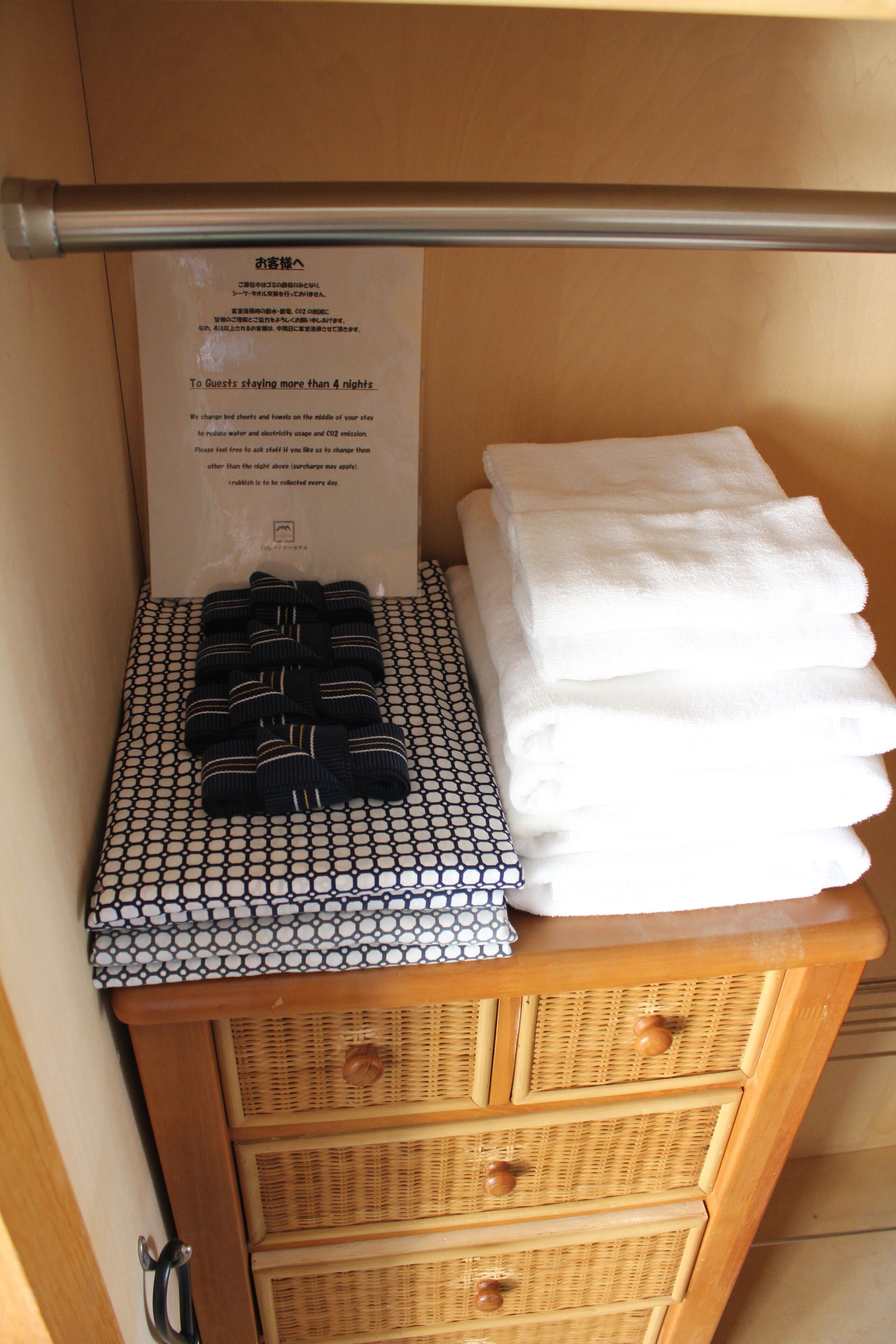 A wooden cabinet with a metal rod, a sign, and folded towels.