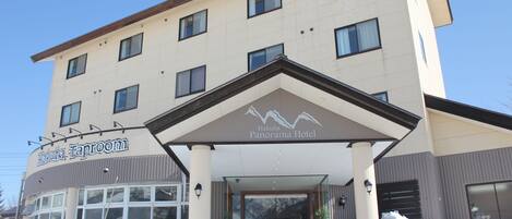Experience the sleek entrance of Hakuba Panorama Hotel, featuring a glass canopy and the Hakuba Taproom sign.