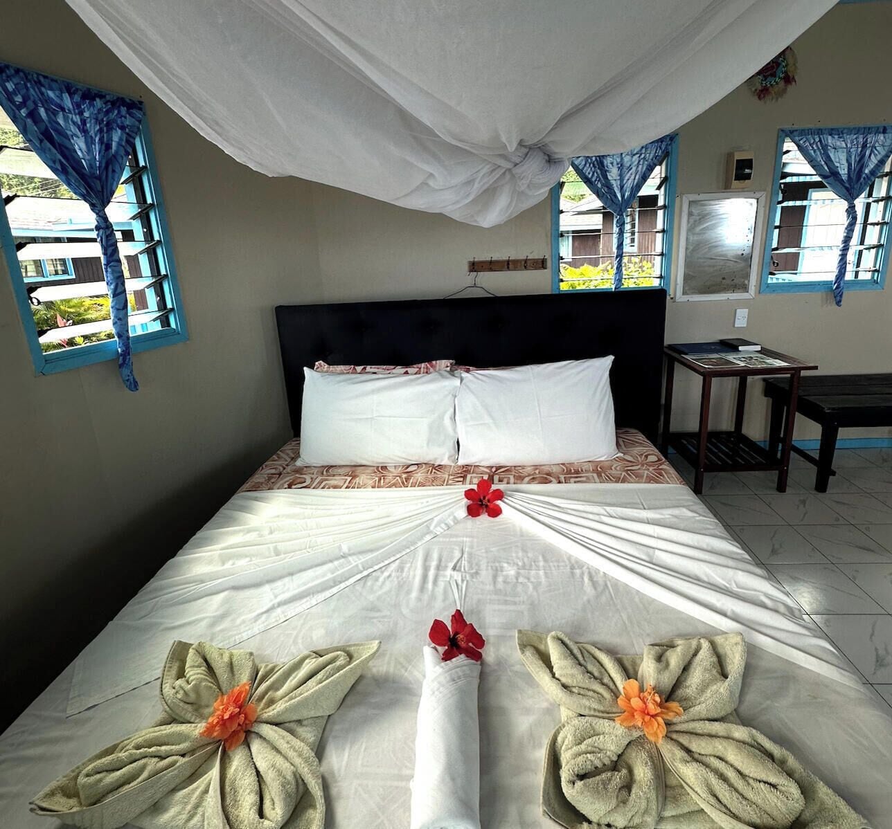 A hotel room with a bed, pillows, a table, and curtains.