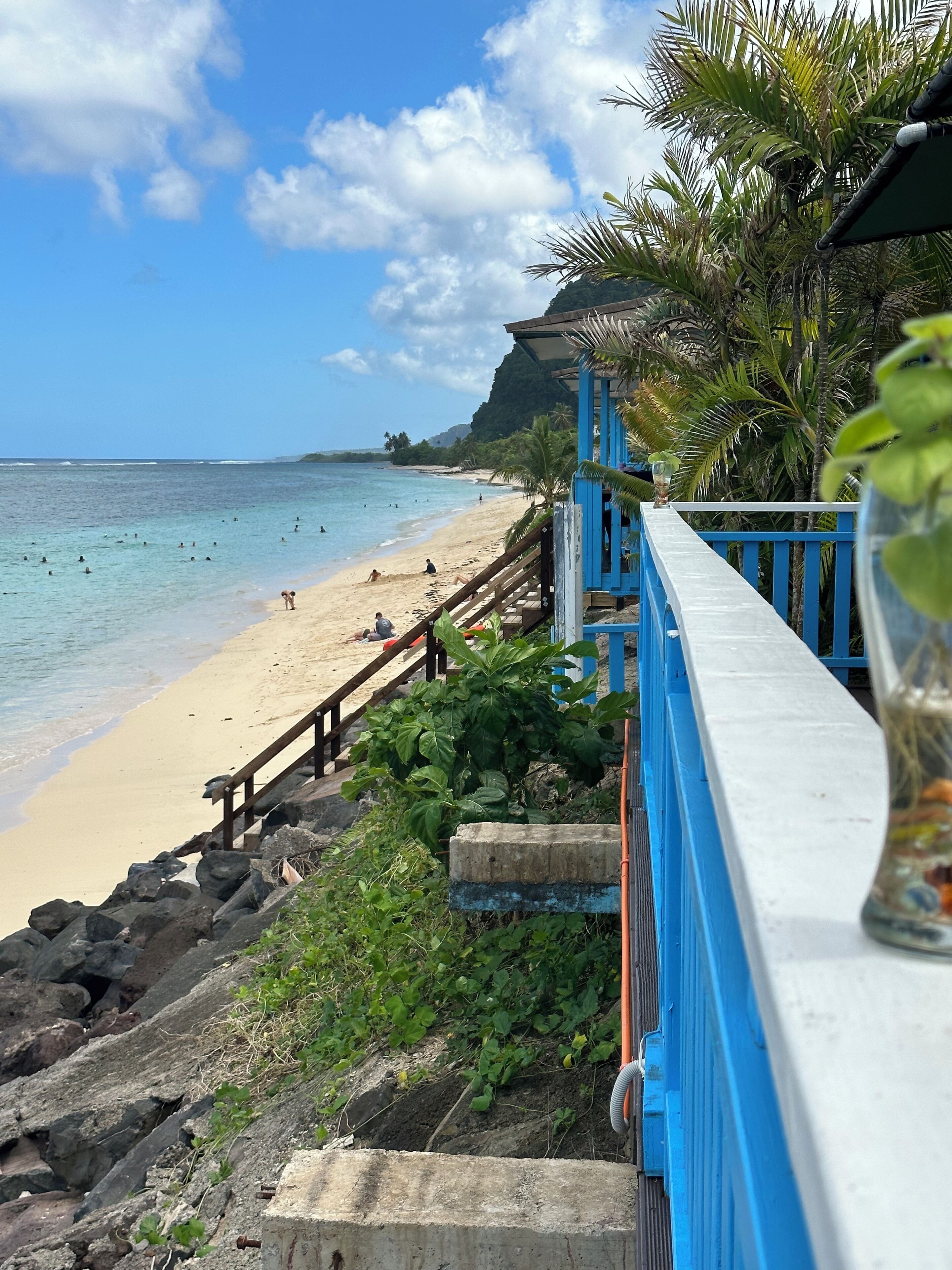 A beach with a wooden walkway and a blue railing overlooking the ocean.