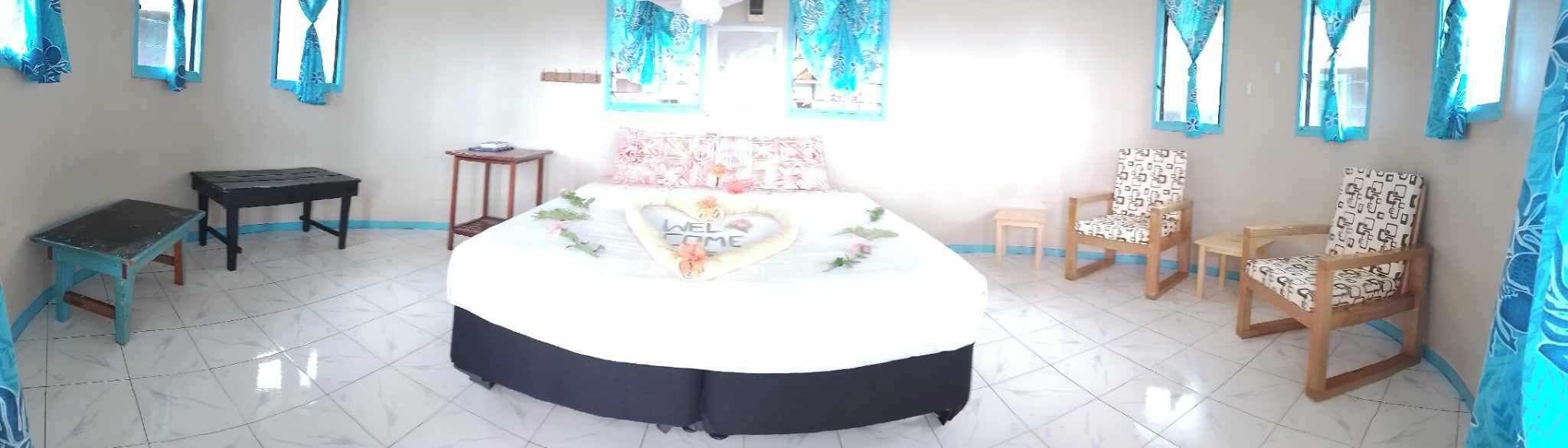 Une pièce comprenant un lit, une petite table, deux chaises et une fenêtre avec des rideaux.