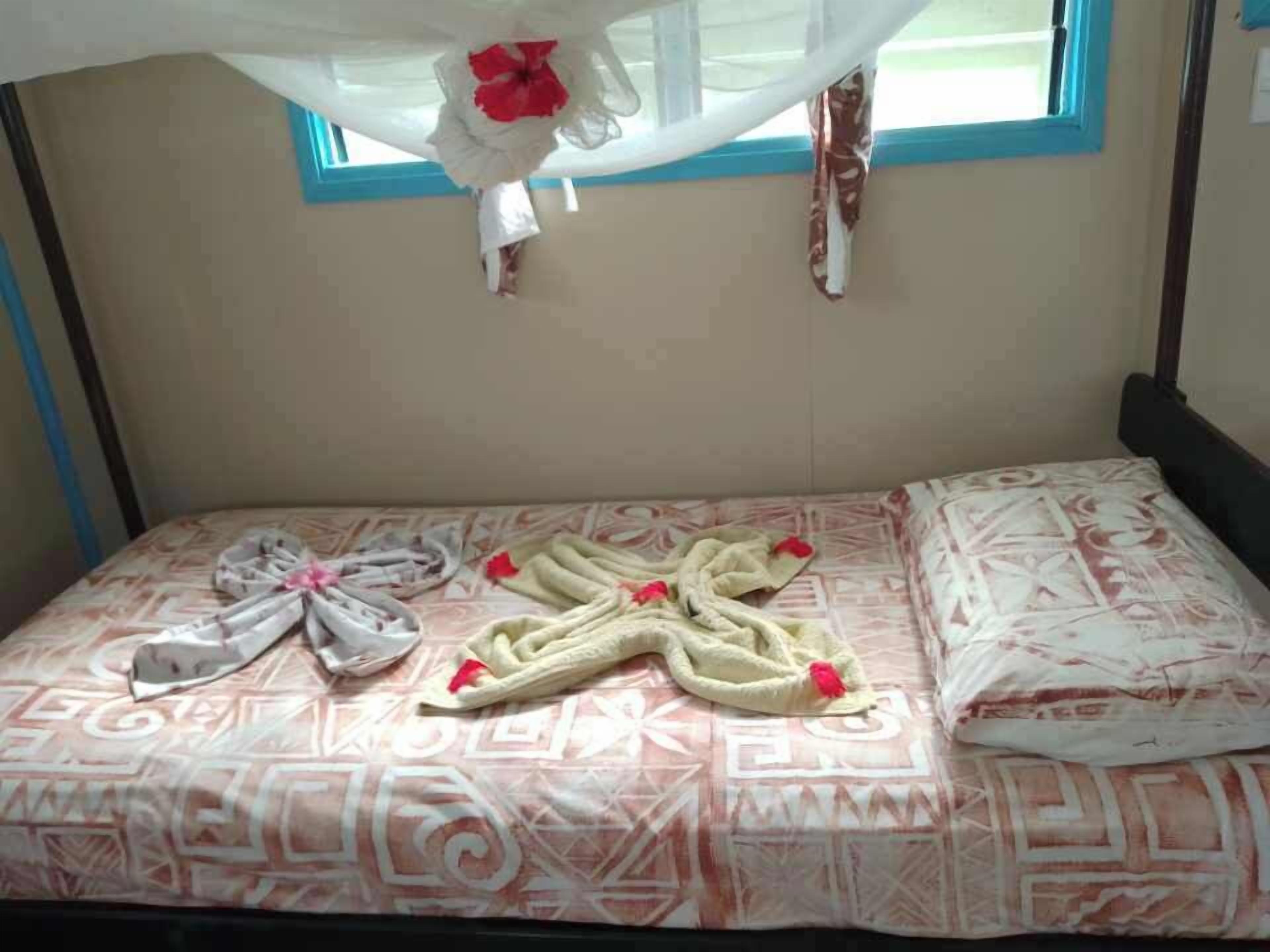 Un lit avec une couvre-lit à motifs, un nœud décoratif et un baldaquin.