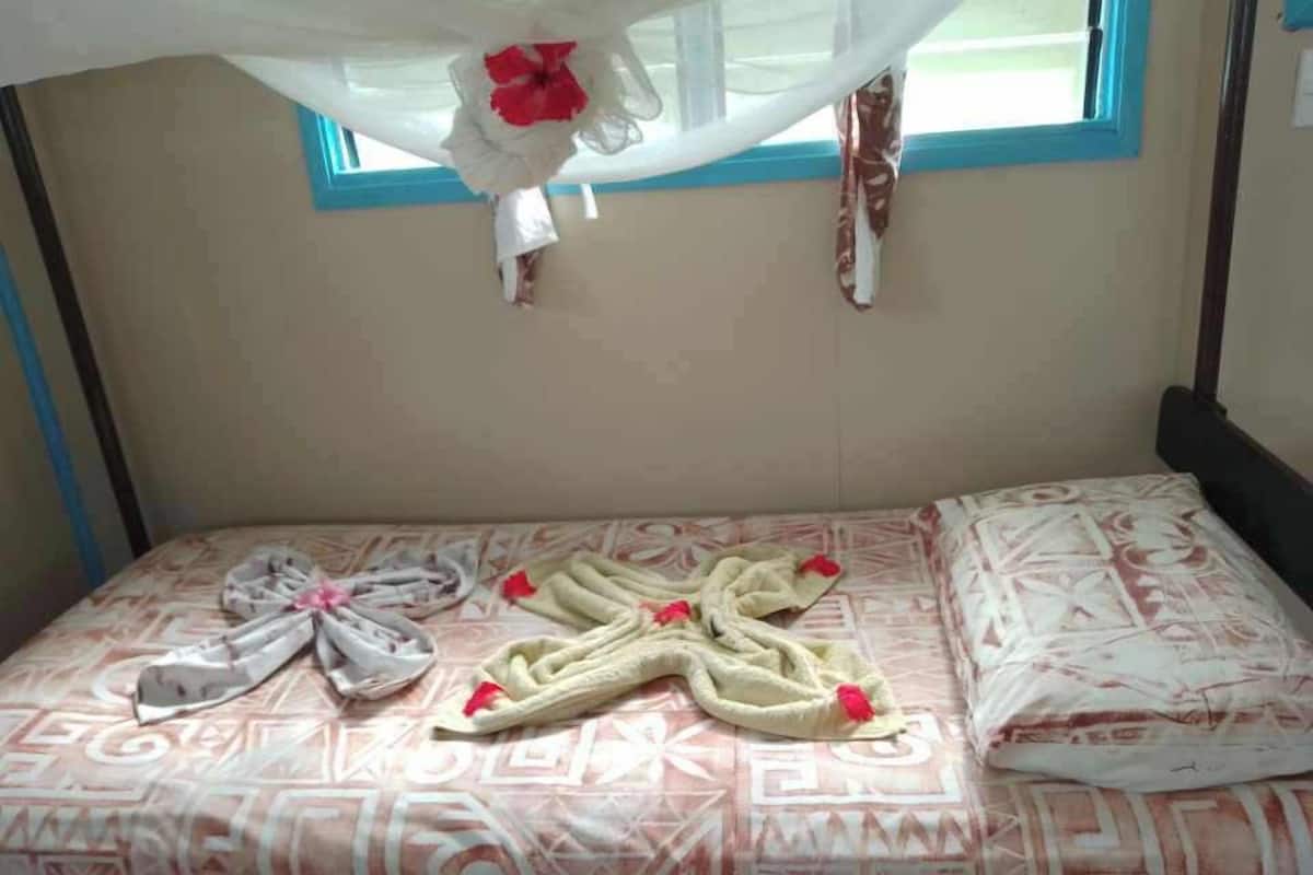 Ein Bett mit einem gemusterten Bettüberwurf, einer dekorativen Schleife und einem Baldachin.