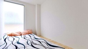 A bedroom with a large window, a bed with a striped blanket, and a wooden floor. - Osaka Namba Hostel MIYABI (Osaka)