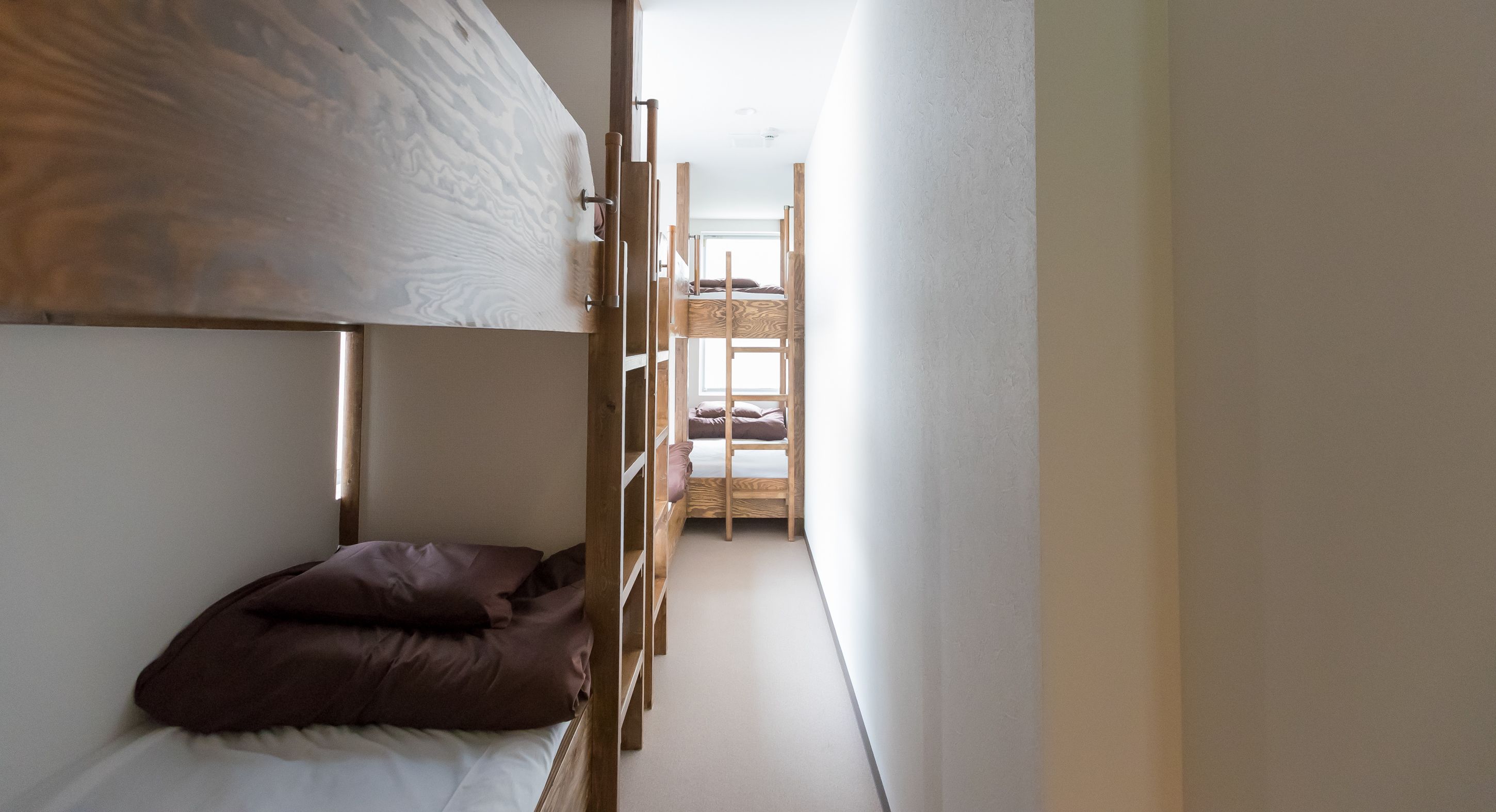 A narrow room with bunk beds and a wooden ladder.