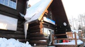 Een blokhut met een sneeuwbedekte dak en een trap naar de ingang.