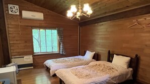Een houten kamer met twee bedden, een raam met gordijnen, een plafondventilator en een kroonluchter.