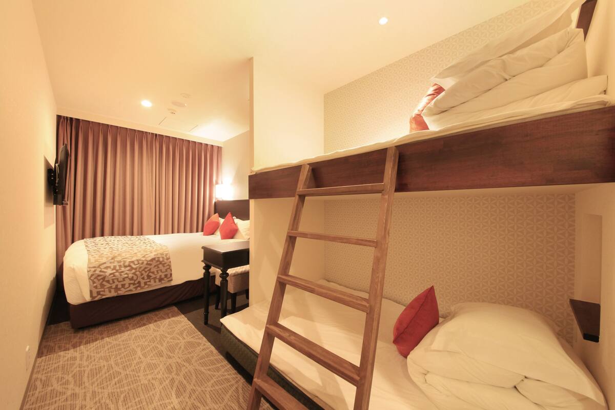 A hotel room with a bunk bed, a desk, and a chair.