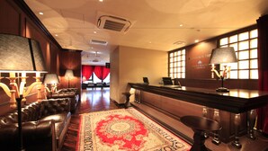 A lobby with a leather sofa, a bar area, and a patterned rug.