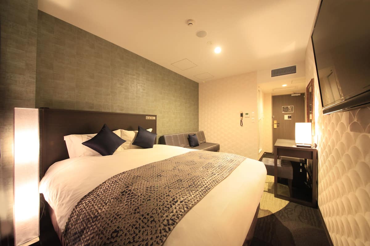 A hotel room with a large bed, a desk, and a television.