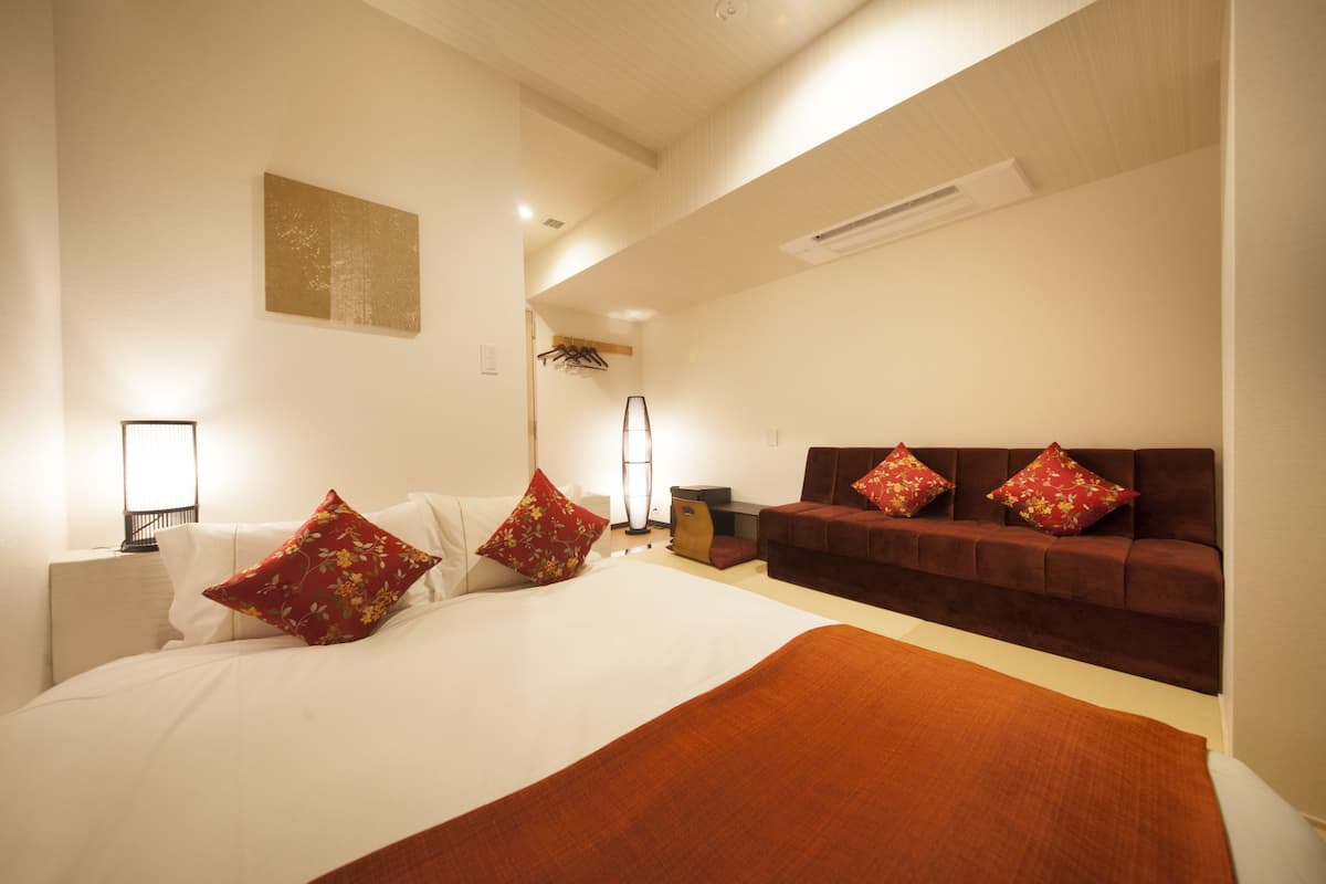 A hotel room with a large bed, a brown sofa, and a small table.